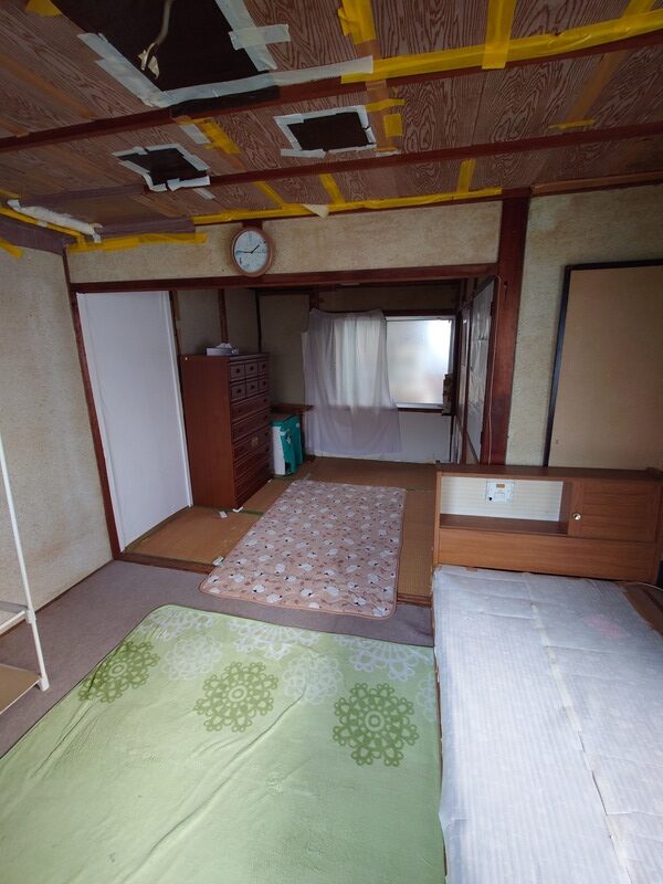 兵庫県尼崎市上ノ島町の空き家2階の和室。天井に雨漏り補修のテープが貼られ、布団やタンスが残る