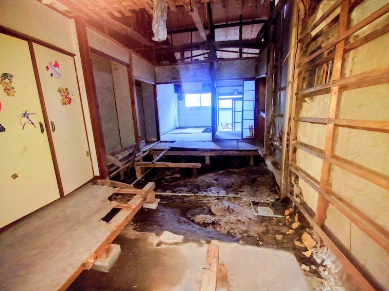 大阪府枚方市渚栄町の空き家の部屋の奥から見た室内、床下の湿った地面が露出している様子
